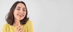 young woman brushing teeth and smiling